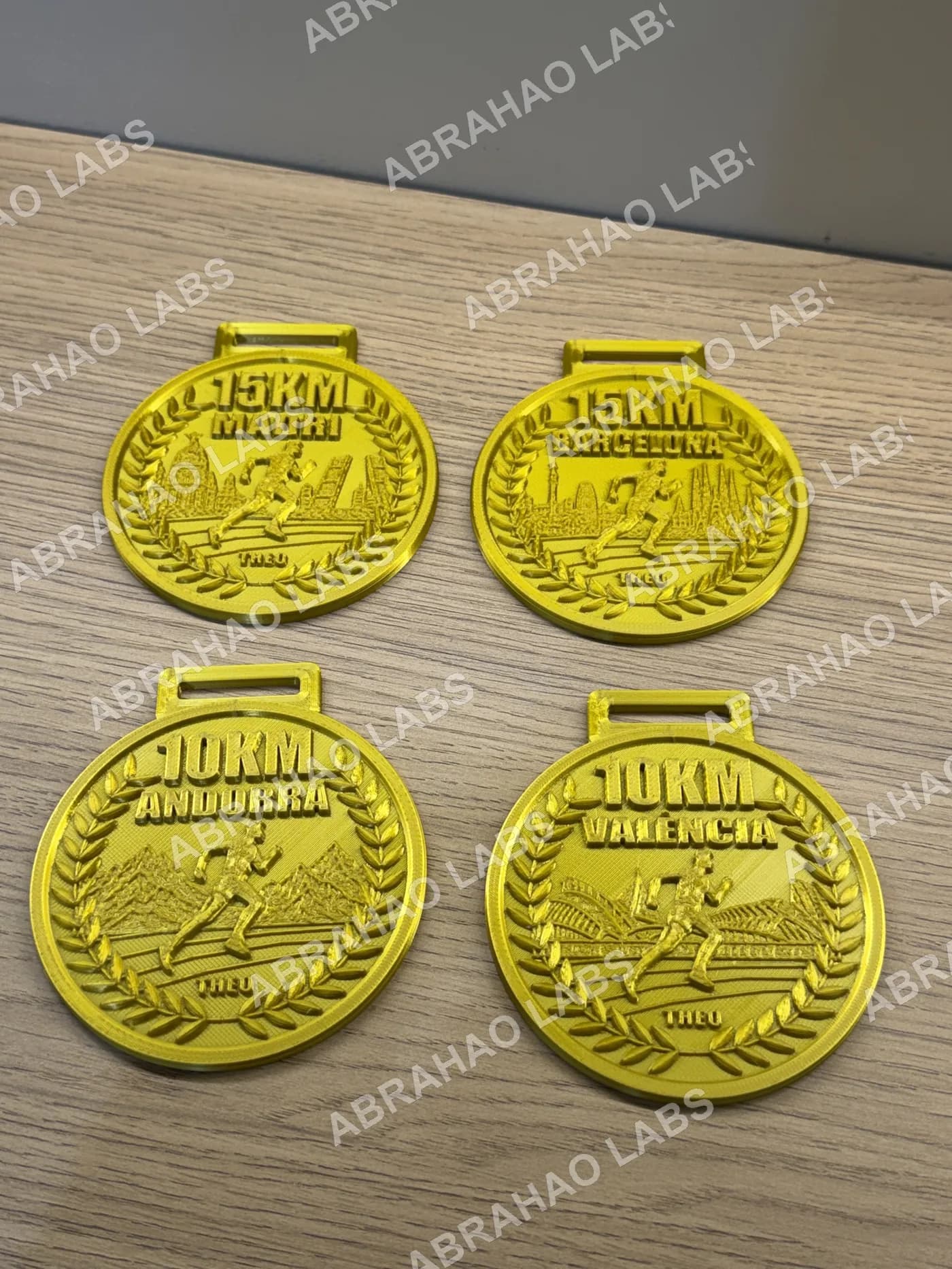 As 4 medalhas do desafio esportivo lado a lado sobre a mesa, mostrando o acabamento dourado e a alça para fita